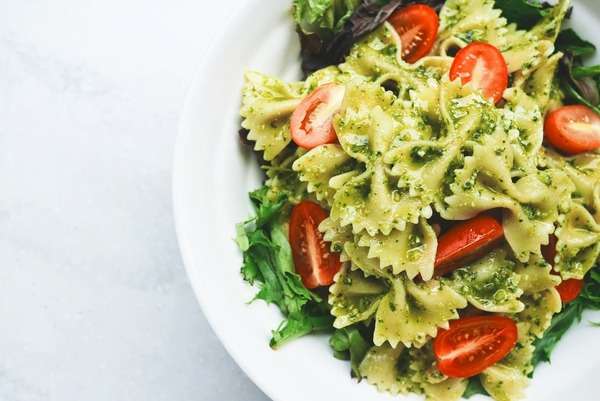 Fresh pasta dish with vegetables and herbs on a bright table
